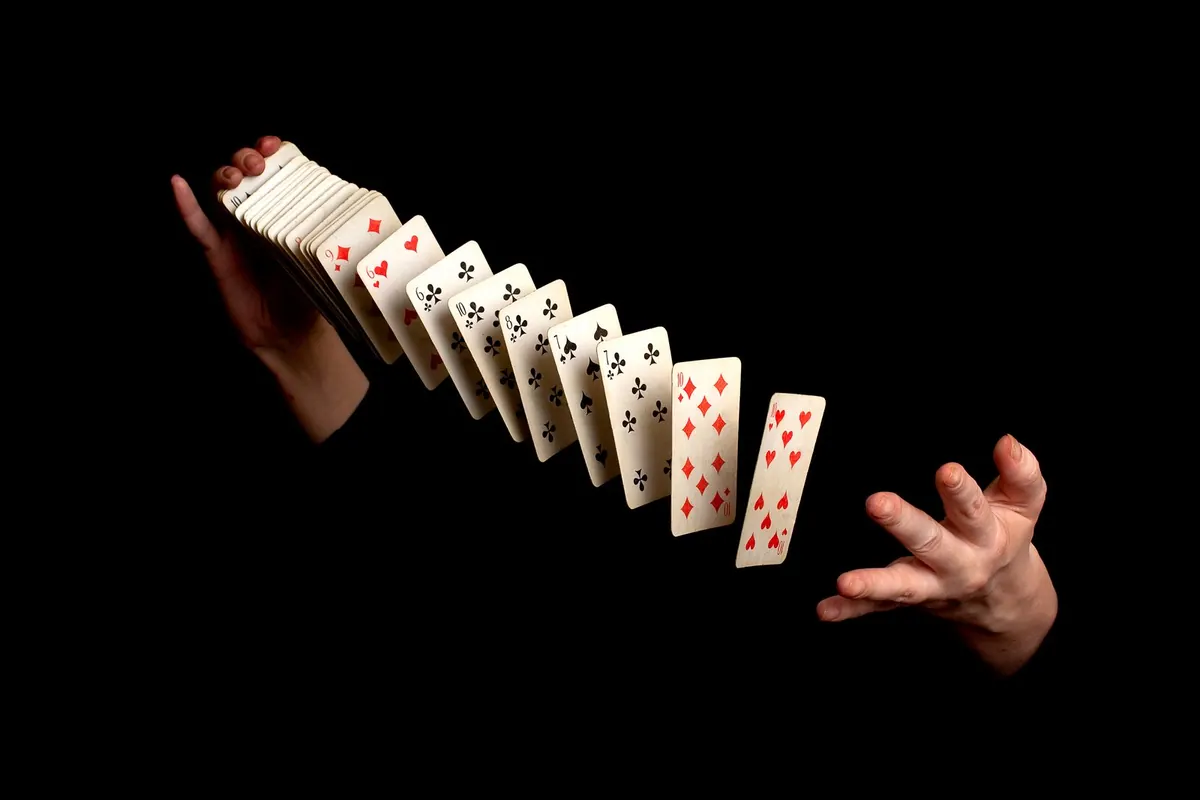 Spielkarten schweben zwischen den Händen eines Zauberkünstlers.