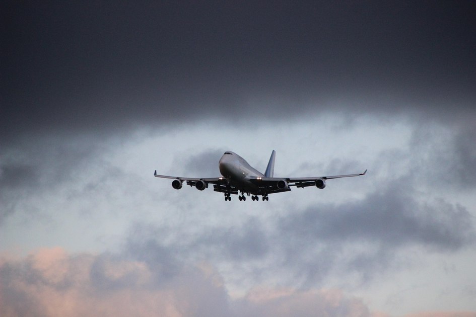 Ein großes Passagierflugzeug befindet sich vor einem bewölkten Himmel im Landeanflug.