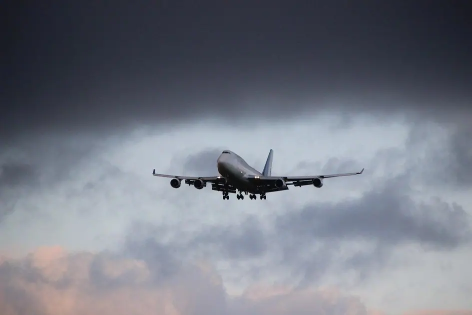 Ein großes Passagierflugzeug befindet sich vor einem bewölkten Himmel im Landeanflug.